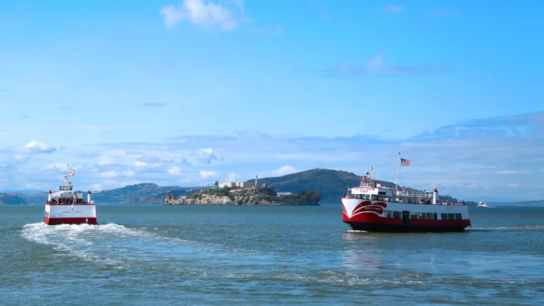 Red and White Fleet bay cruise boat sailing past Alcatraz Island in San Francisco Bay.