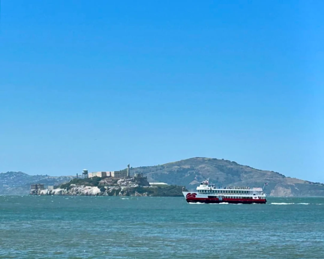 Red and White Fleet sightseeing boat cruising past Alcatraz Island in the San Francisco Bay.